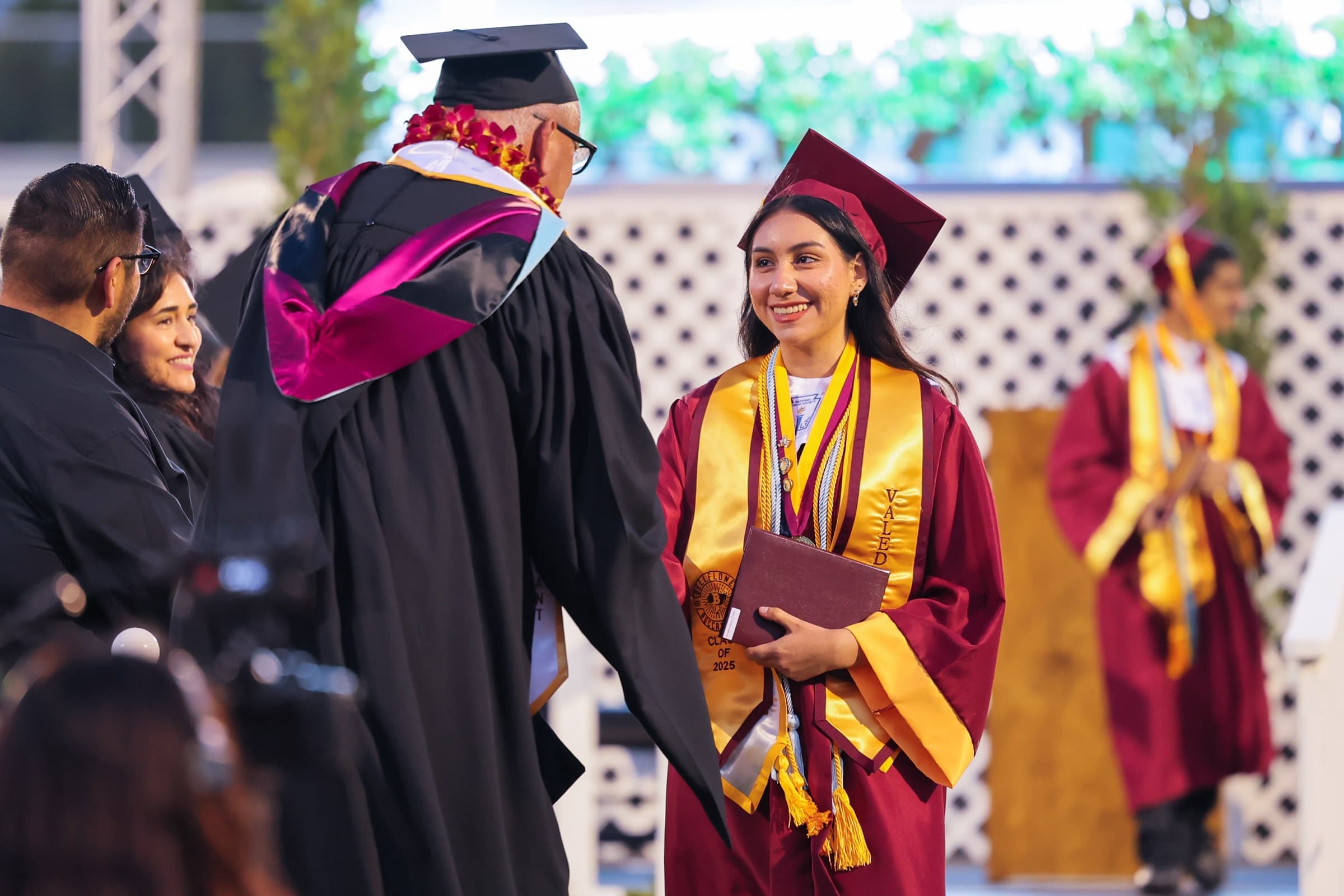A Bellflower Unified valedictorian smiles while receiving her diploma on stage