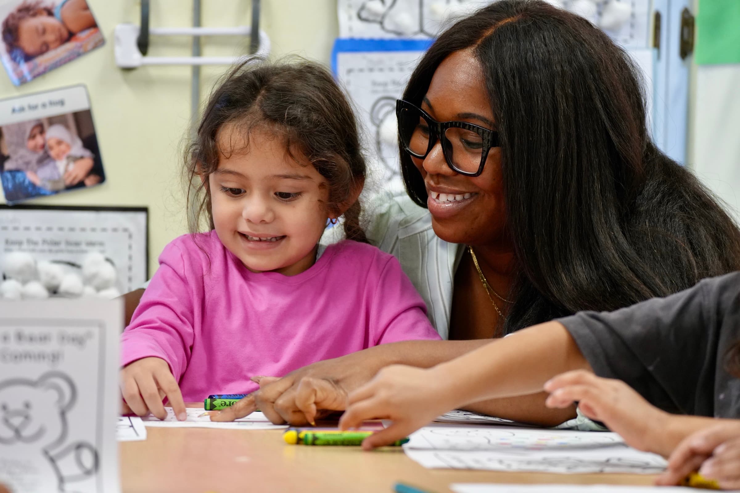 A teacher and a young Bellflower Unified student color together in class