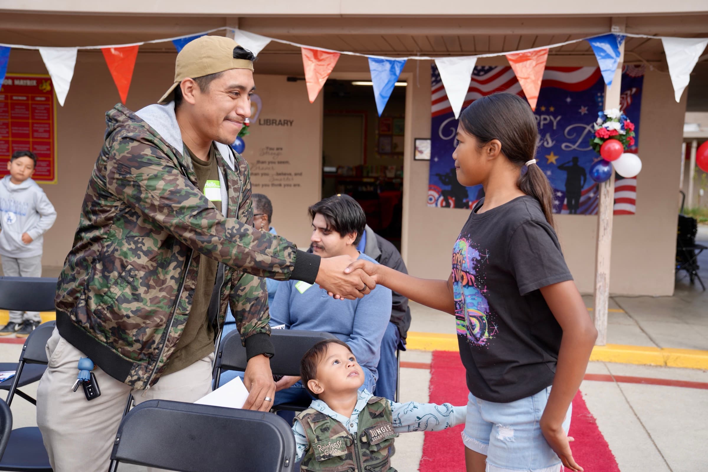 A student greets a visiting community member during a school event