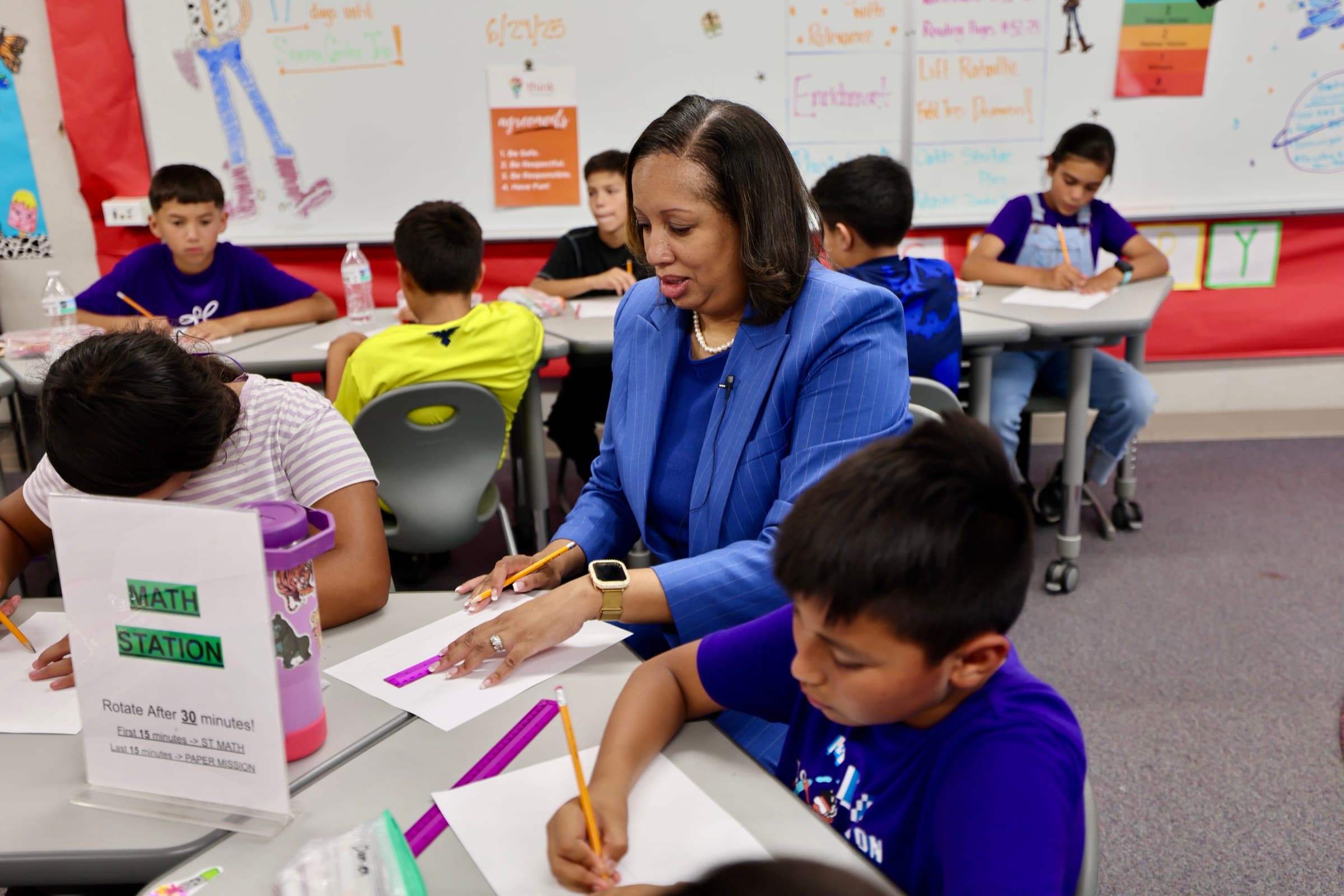 A teacher works with Bellflower Unified students at a classroom math station